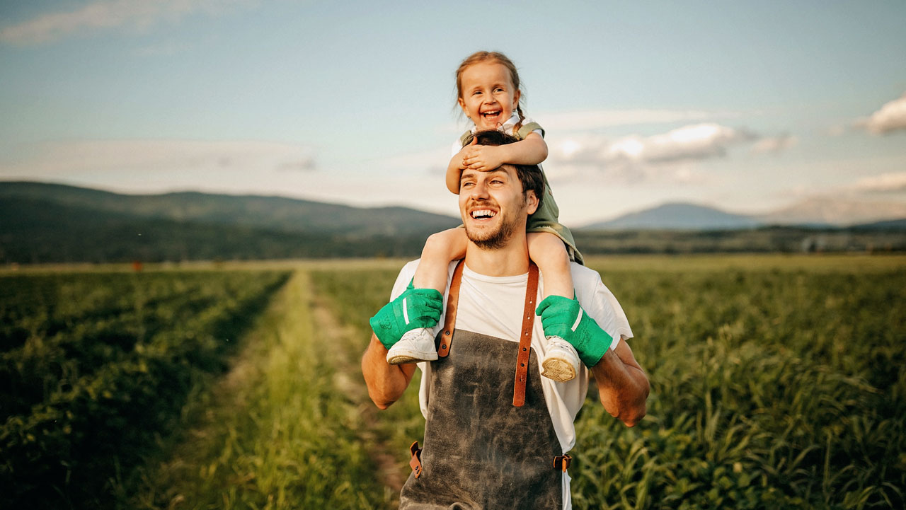 Father carrying his daughter on the famr land